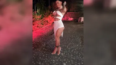 Denise senza veli con mini abito bianco all'aperto